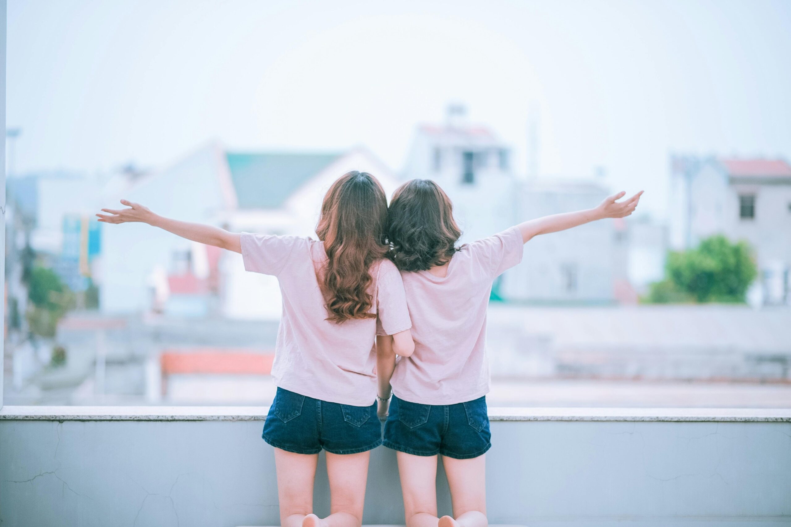 Two women embracing while facing a scenic backdrop, sharing joyful moments.